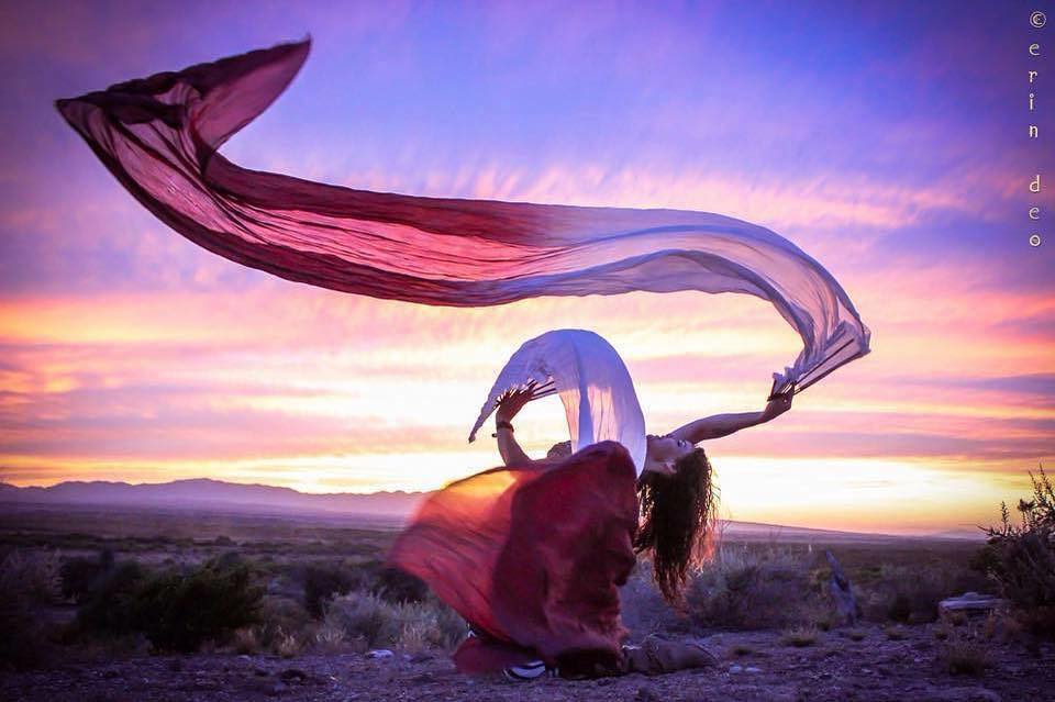 Melodia performing with flowing silk veils beneath a vibrant sunset sky, embodying the creativity, movement, and artistic expression that define her unique journey.