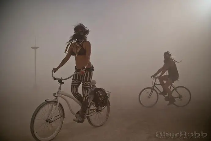 Melodia and Ian ride bicycles through a Burning Man dust storm on their way to enjoy a festive potato salad recipe.