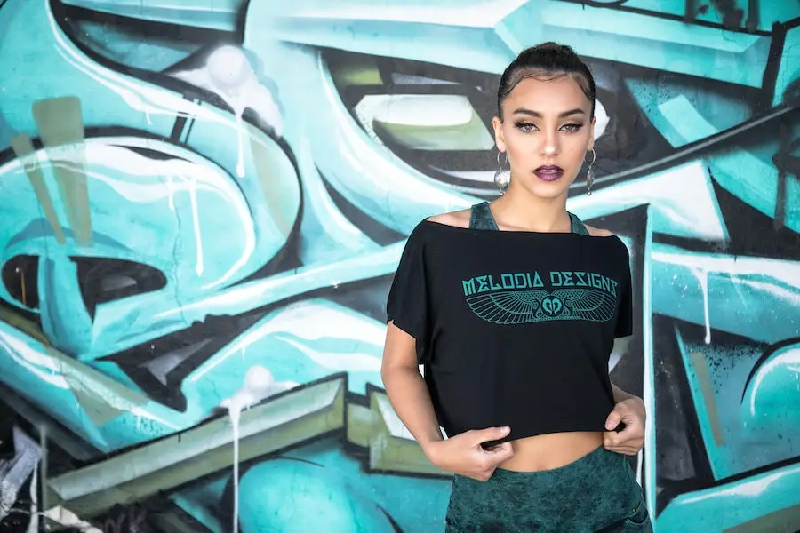 Model wearing cropped logo top from the Limited Edition Grunge Collection against a teal graffiti wall
