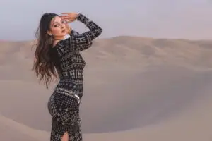 Woman wearing alkimiya nawal obsidian posing on sand dunes