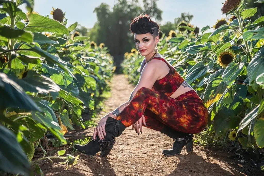 Glamourous model squatting in sunflower field for the Melodia Designs Fall Holiday Capsule Collection.