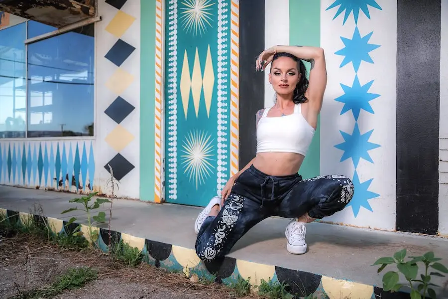 Tracy posing in Spellbound Collection against colorful mural by Shrine.