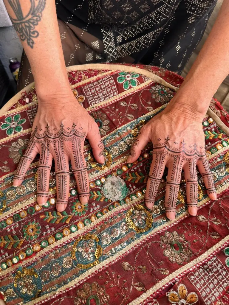 henna decorated hands resting on colorful embroidered textile
