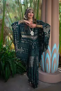 Model wearing the Malachite Assuit kaftan styled in a lush indoor setting.