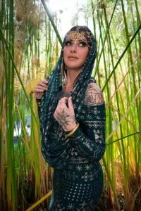 Model wearing the Malachite Assuit hooded top styled in a natural reed setting.