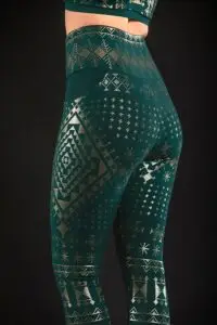 Model wearing the ELSA Assuit bamboo pocket leggings in malachite green with gold geometric patterning.