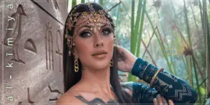 Model wearing the Al-Kimiya Malachite Assuit long-sleeve top with gold geometric detailing, styled with ornate jewelry in a natural setting.