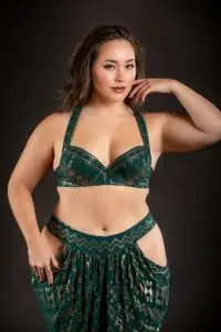 Model wearing the Vixen Assuit bra in malachite green with gold geometric patterning.