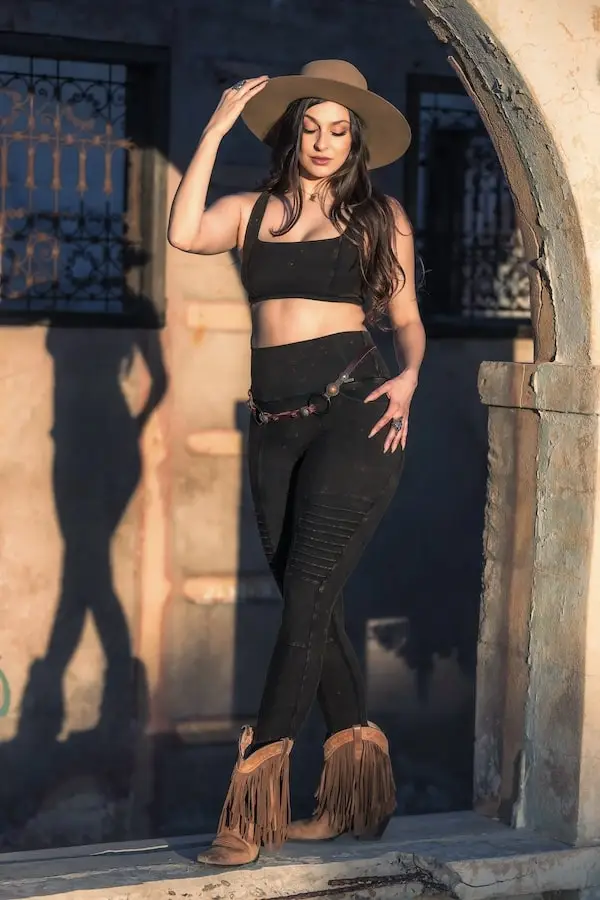 Model tipping her hat to the shadows in Rustique outfit, evoking strength, femininity, and ease of movement.
