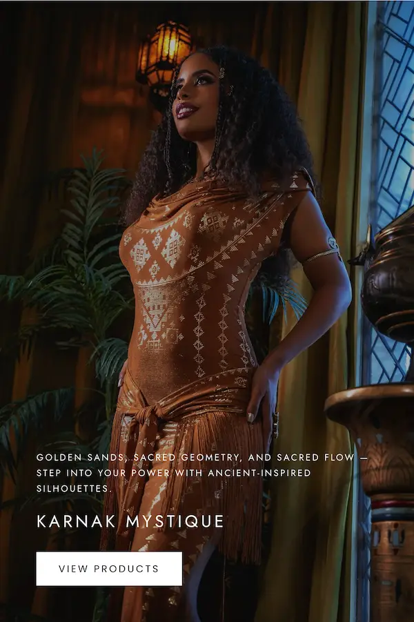 Model wearing a copper Karnak dress with geometric patterns and a draped neckline, styled indoors in a warm, ornate setting.