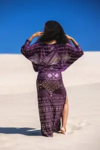 Back view of a purple Karnak dress styled in a bright desert setting with flowing movement.