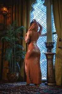 Back view of the copper Karnak outfit, showcasing the open-back design and fluid skirt movement.