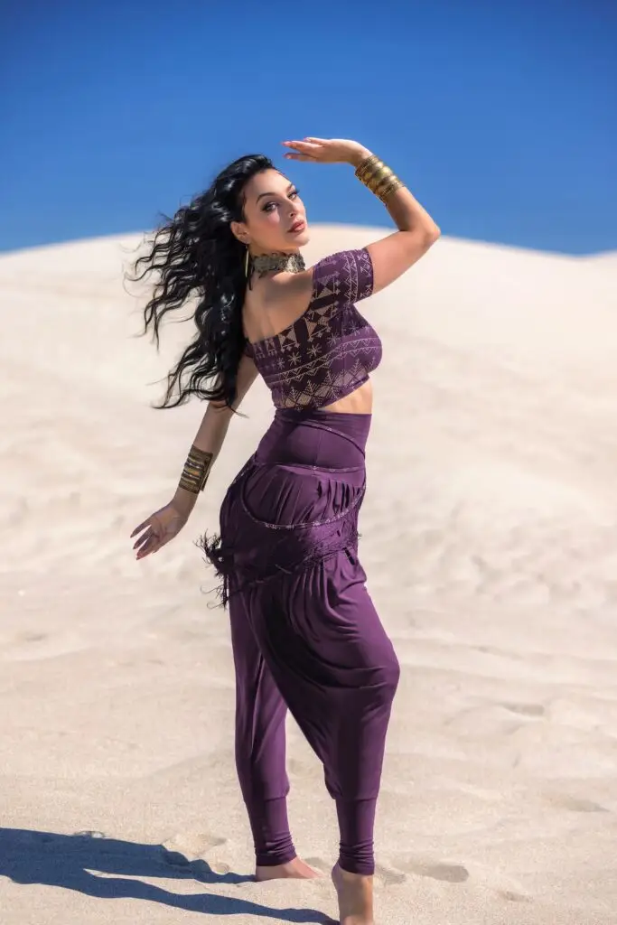 Model poses in aubergine Alkimiya Allie crop top and Jazmine Harem Pant — a desert-ready design for expressive, empowered movement.