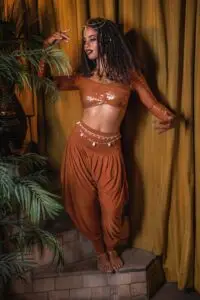 Model wearing the Karnak Mira wrap top and Jazmine harem pants in copper, styled as a coordinated two-piece set.