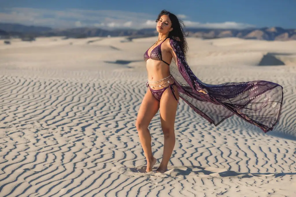 Woman wearing karnak zsa zsa robe aubergine outfit with flowing scarf on white sand dunes