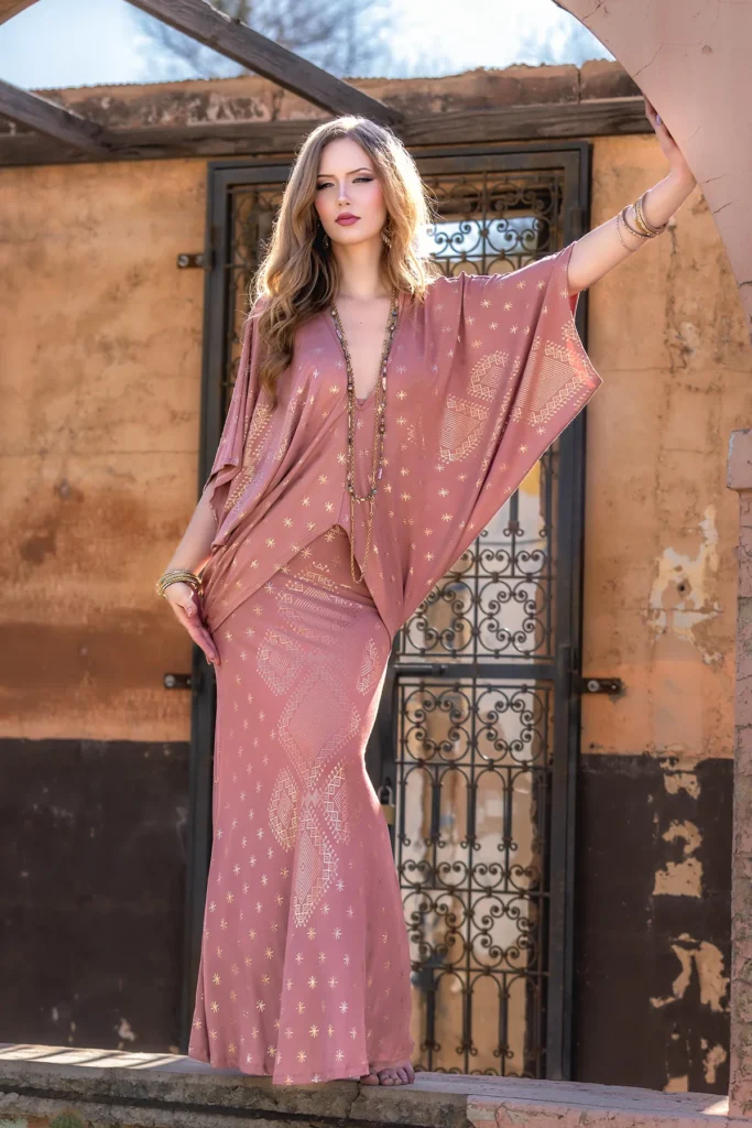 Model posing in the Desert Rose Dendera Collection skirt coupled with draped wing sleeved blouse and shimmering sacred geometry accents, inspired by ancient Egyptian elegance.