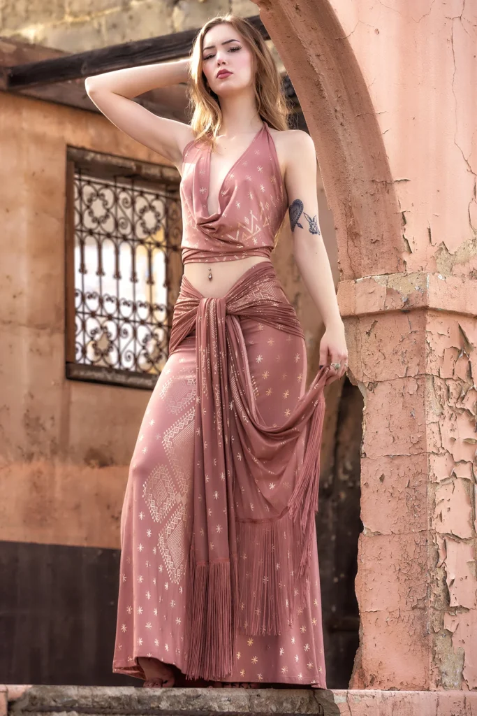 Full-length view of the Desert Rose Dendera Collection gown featuring intricate gold geometric detailing and flowing fabric against a warm sandstone backdrop.