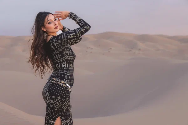 Woman wearing alkimiya nawal obsidian posing on sand dunes